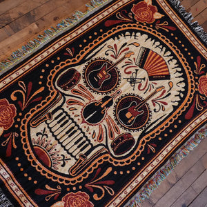 Woven skull blanket with musical instruments.