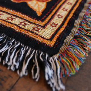 Woven blanket with colorful fringe.