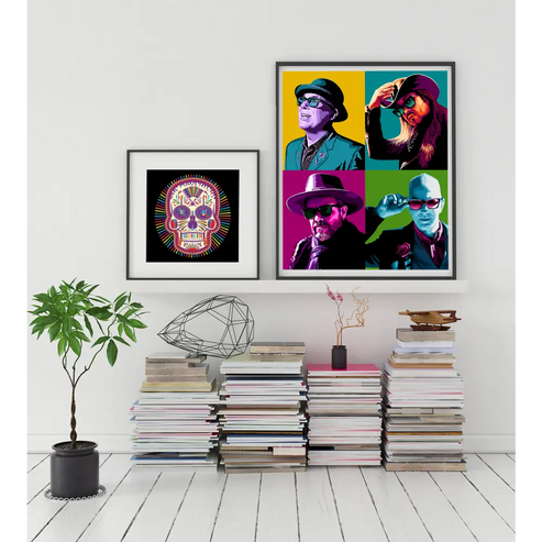 Colorful pop art-style portraits displayed alongside a framed sugar skull image above stacks of books.